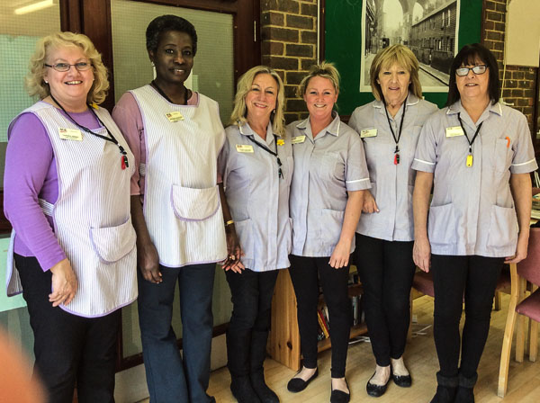 Six female care staff in uniform pink aprons
