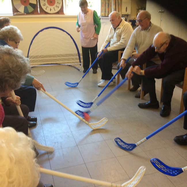 Image of clients seated playing a game of chair hockey